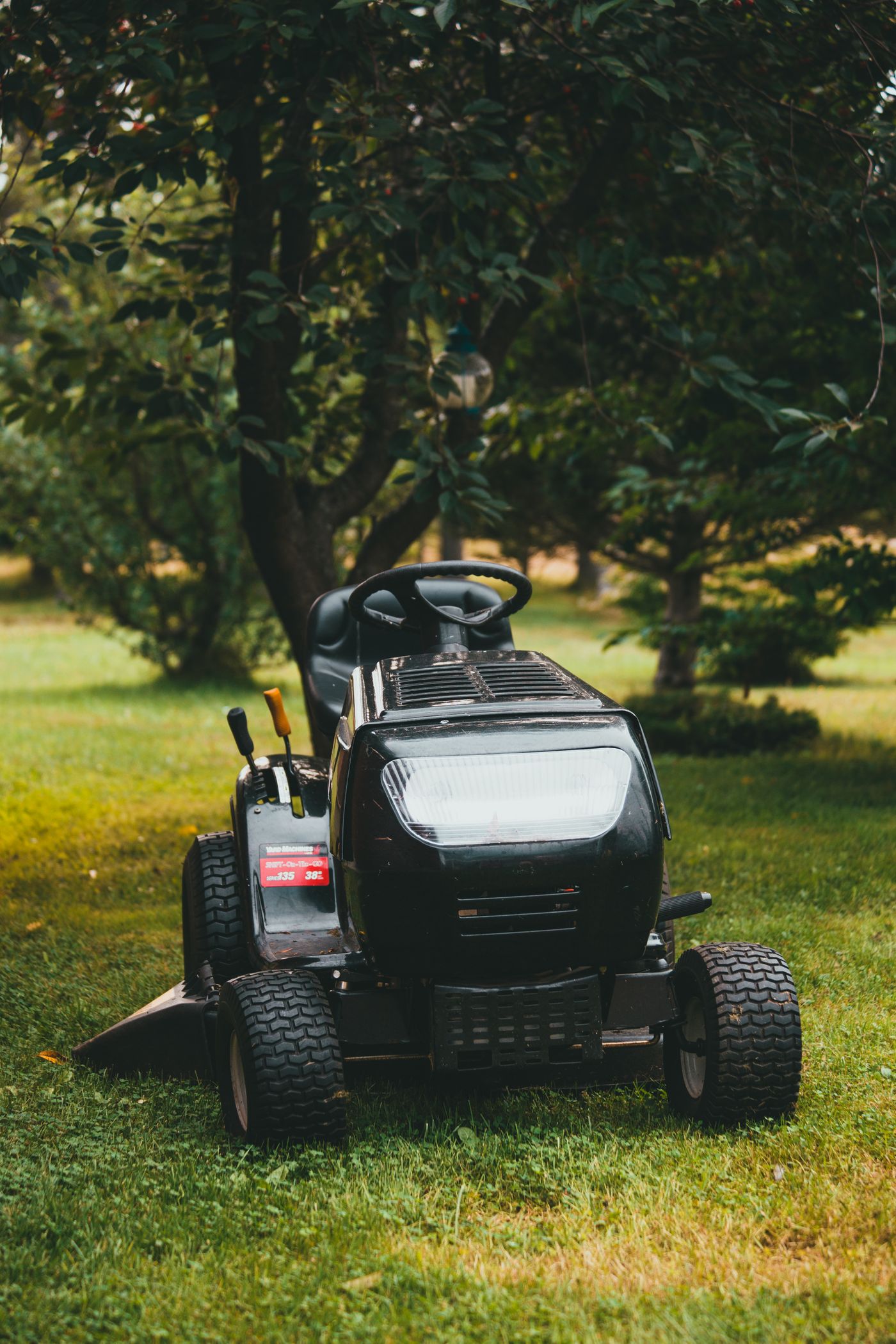 Commercial riding mower cutting a green residential lawn